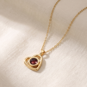 Gold Hidden Photo Necklace laid on cream linen with the chain in a loose curve