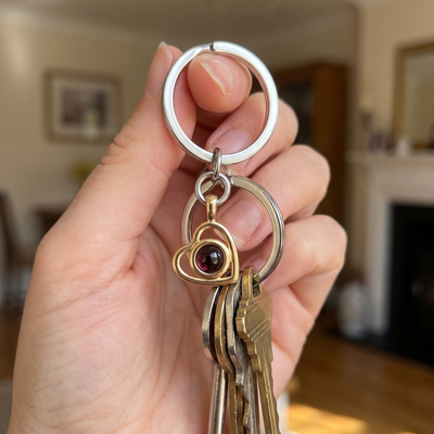 Gold Hidden Photo Keychain held in the hand with house keys, the heart charm and projection lens in view