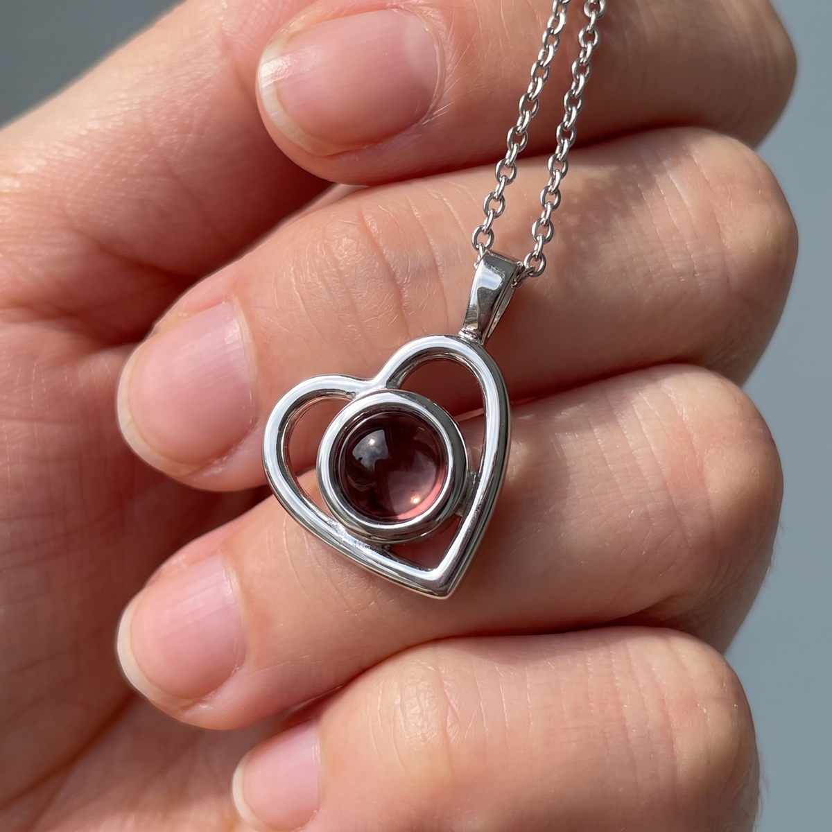 Silver Hidden Photo Necklace held between finger and thumb