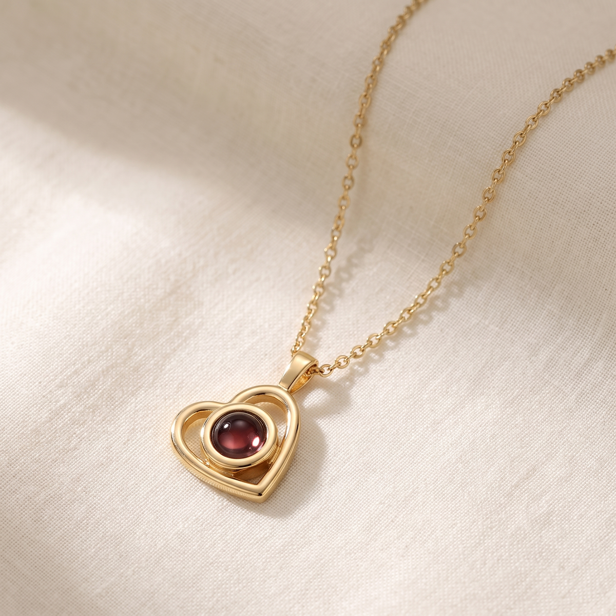 Gold Hidden Photo Necklace laid on cream linen with the chain in a loose curve