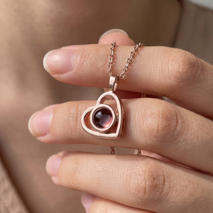 Rose gold Hidden Photo Necklace held close, showing the projection lens in its bezel