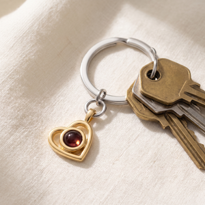 Gold Hidden Photo Keychain resting on cream linen beside a set of keys